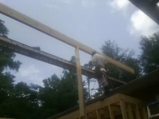 Carpenter setting a ridge beam over a new addition frame — Ice Dam Removal by Roofing Brothers in Alpena
