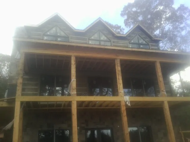 Dormers and porch framing on a large log home under construction — Roof Coating work by our crew in Alpena