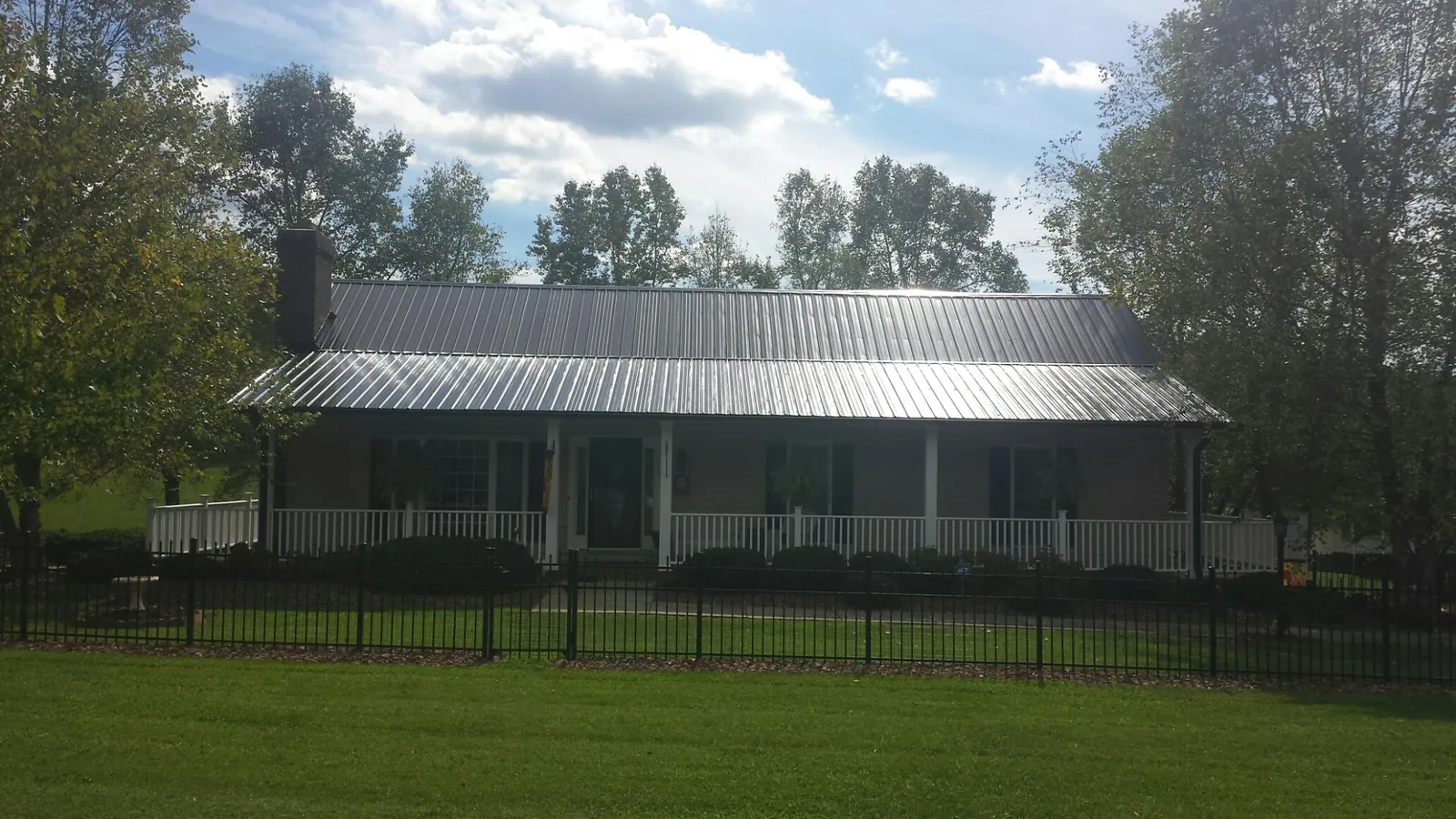 Gray metal roof on a brick ranch with a full width front porch — Gutter Guard Installation work by our crew in Alpena