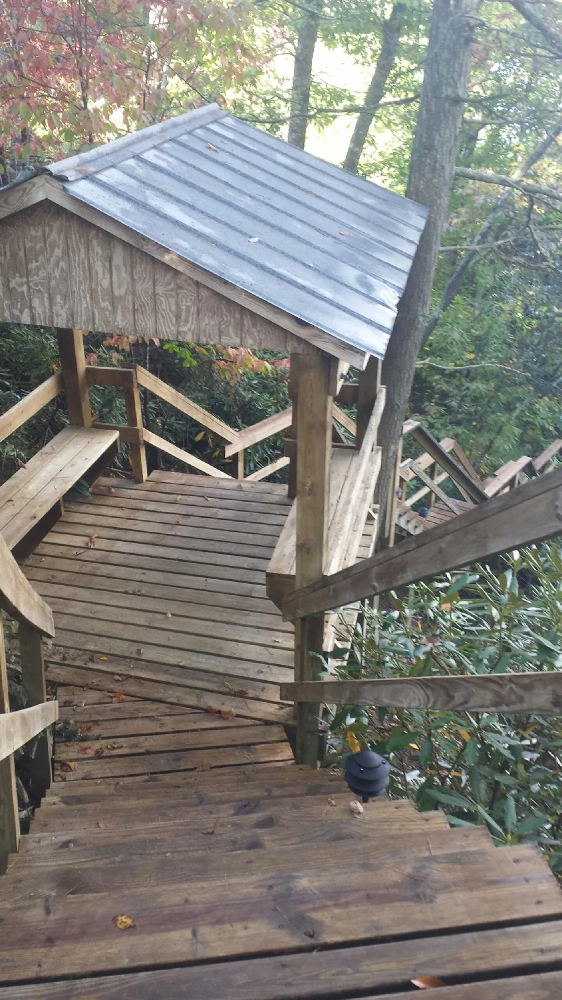 Metal roofed shelter over wooden steps on a wooded walkway — Skylight Repair & Installation work by our crew in Alpena