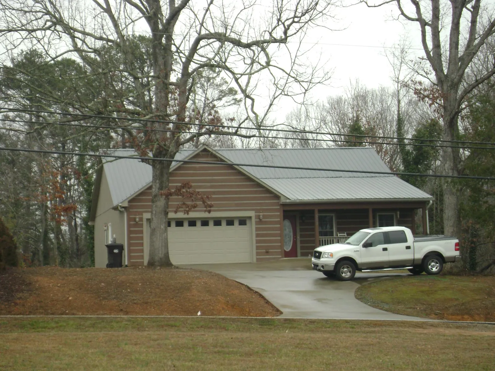 Gray metal roof on a log sided house with an attached two car garage in Alpena