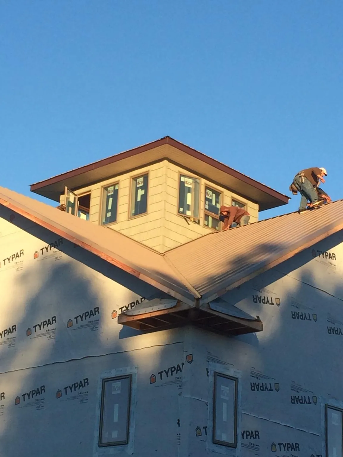 Roofers working around a rooftop cupola on a new metal roof at sunset — Roof Waterproofing in Alpena by Roofing Brothers